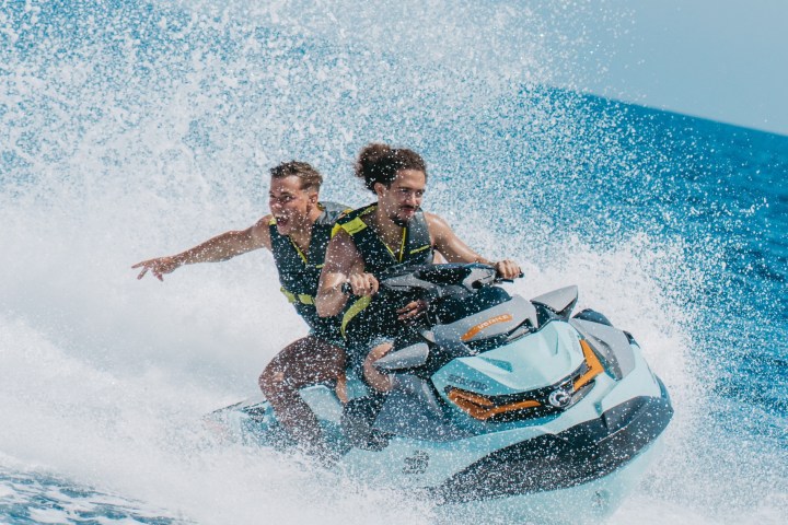 Two people riding a jet ski on the ocean, creating a large splash.