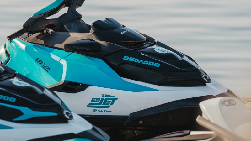 Close-up of lined-up jet skis on calm water.