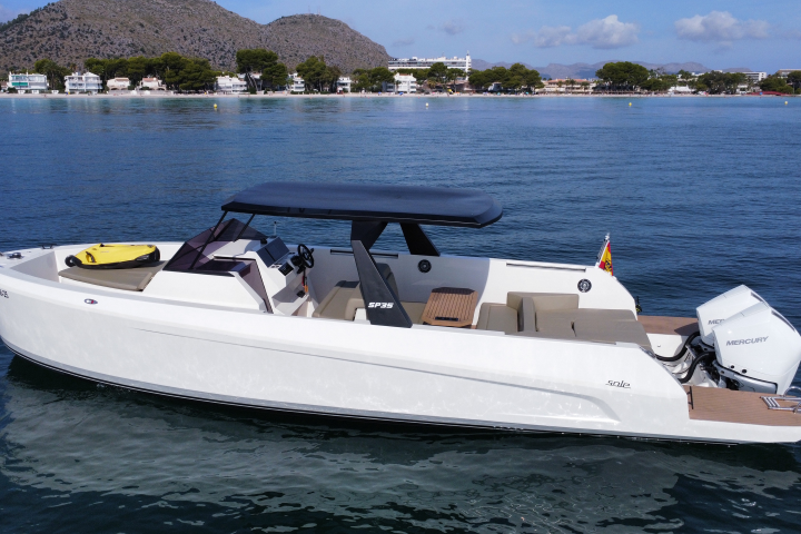 White motorboat on a calm sea with distant shoreline and tree-covered hills.