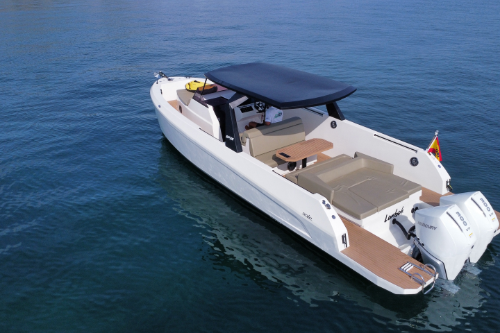 Modern motorboat with seating and sunshade on calm water.