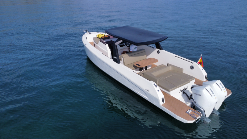 Modern motorboat with seating and sunshade on calm water.