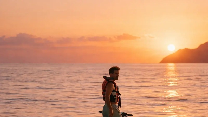Person on a jet ski at sea during sunset, with a mountainous silhouette in the background.